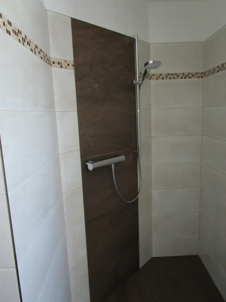 Appartement Hochglocker: bodenebene Dusche mit Fliesen in Holzoptik