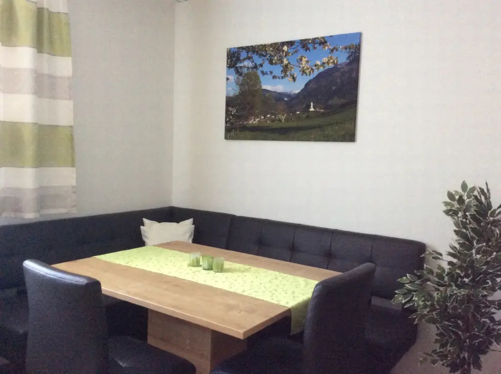 Appartement Hochglocker: Eckbank mit großem Esstisch und Wandbild von St. Veit