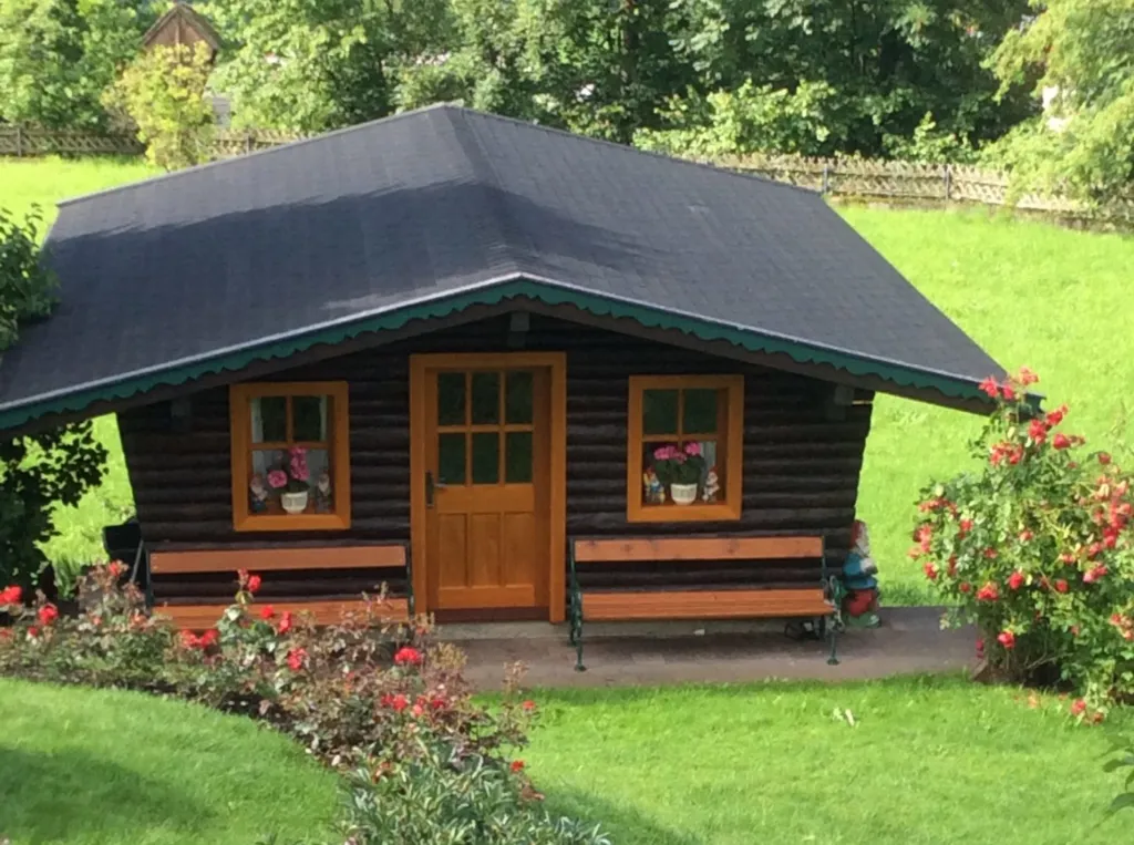 Wooden summer house decorated with flowers on the lawn
