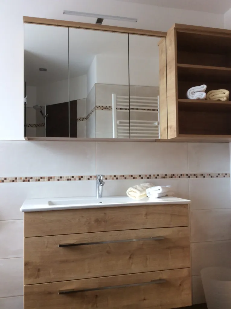 Badezimmer mit Waschtisch aus Holz und Spiegelschrank