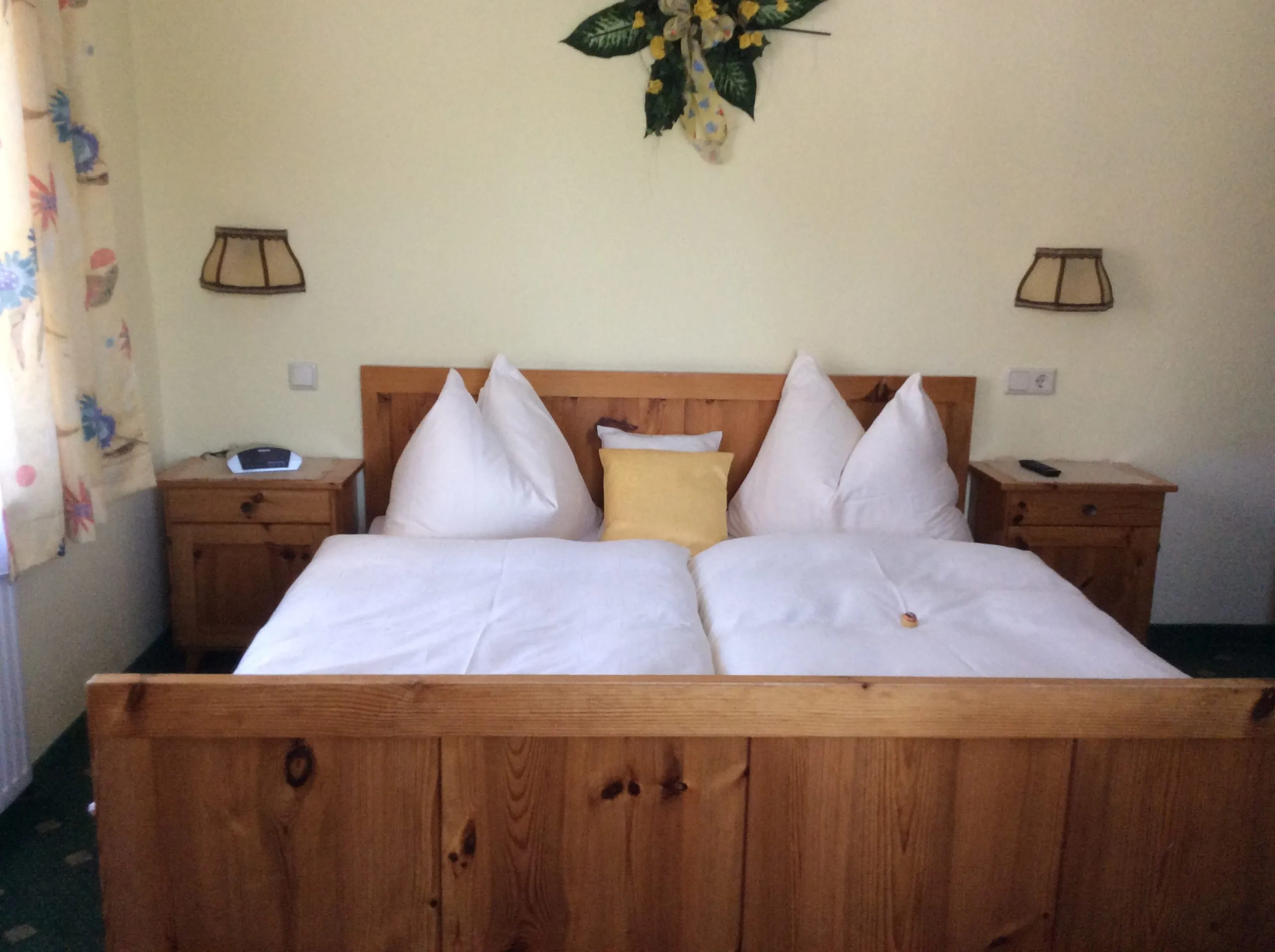 Doppelzimmer mit Holzbett, hellen Wänden und Nachtkästchen