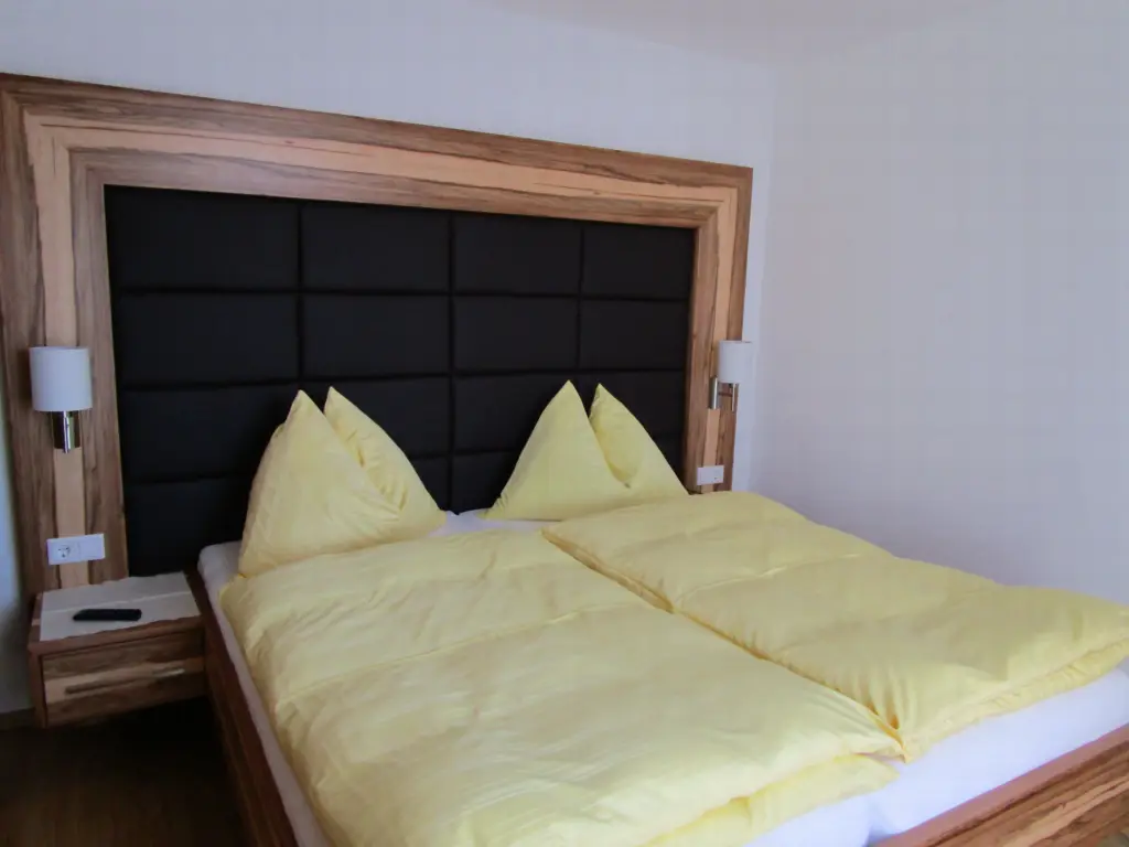 Appartement Schneeberg: Schlafzimmer mit Doppelbett, gepolstertem Kopfteil und Holzrahmen